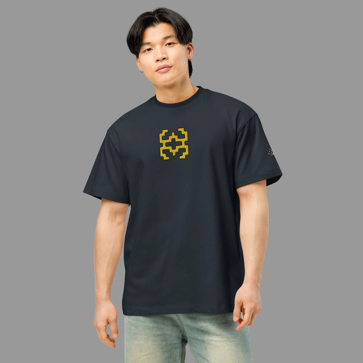 Invaders embroidered box tee in Navy Blazer, front on a person: golden yellow stepped figure with black outline on the chest
