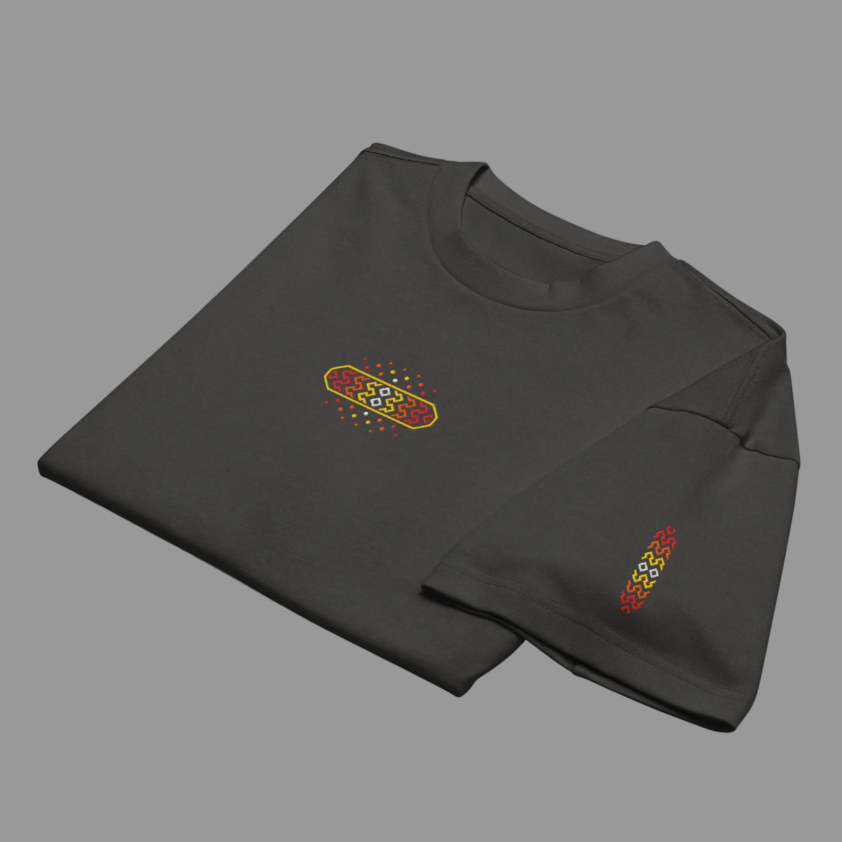 Invaders 2 embroidered box tee in Vintage Black, folded, detail: red to yellow hook badge with white diamonds, sleeve strip