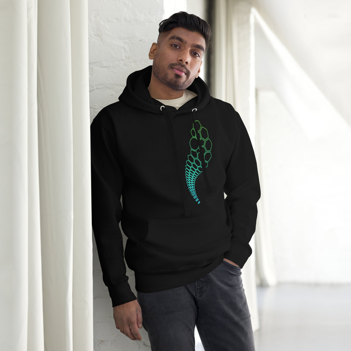 Hexa unisex cotton hoodie in Black, front view on a model by a white wall: hexagon arc on the left chest